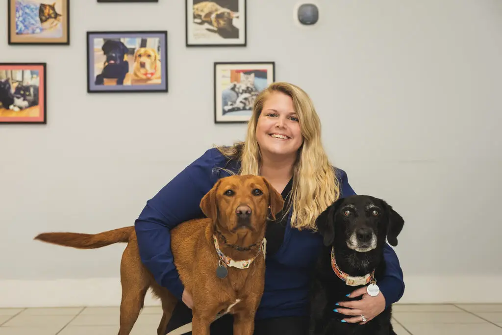 The Arnold Pet Station practice manager poses with two dogs in the lobby.